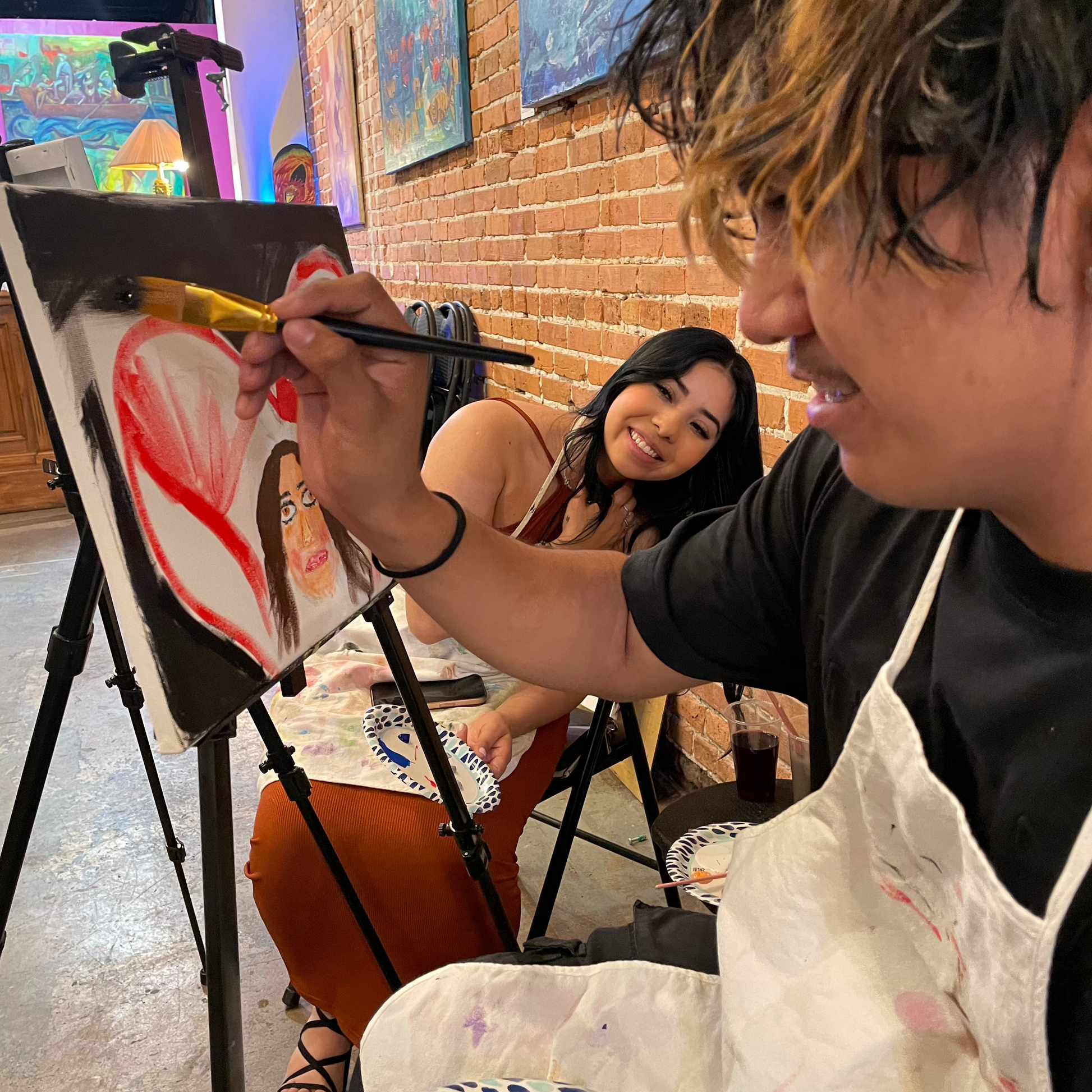Partners creating portrait paintings of each other during the couples sip and paint experience at Marcolina's art gallery.