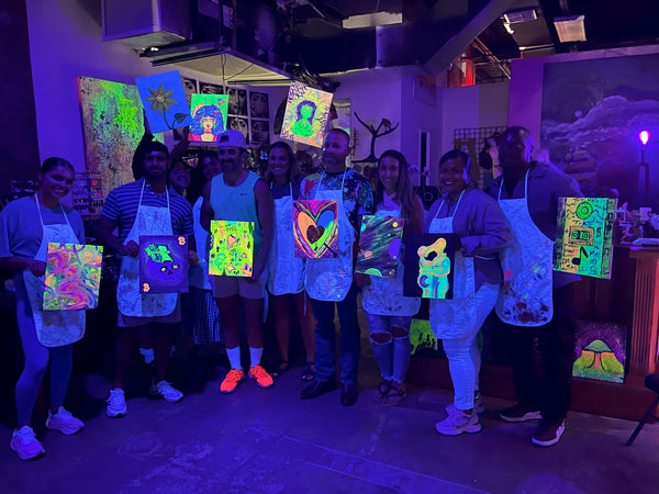 Group holding neon paintings at Marcolina's Neon Nights Tampa