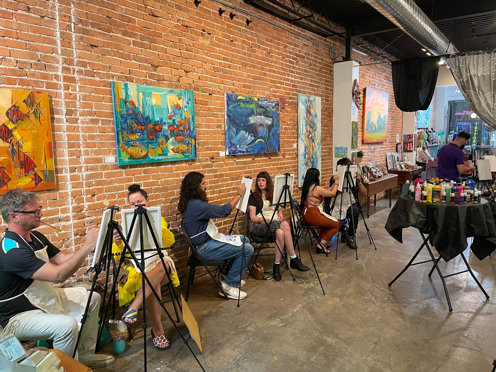 Group of guests painting together during a lively sip and paint session at Marcolina's art gallery in Ybor City, Tampa.