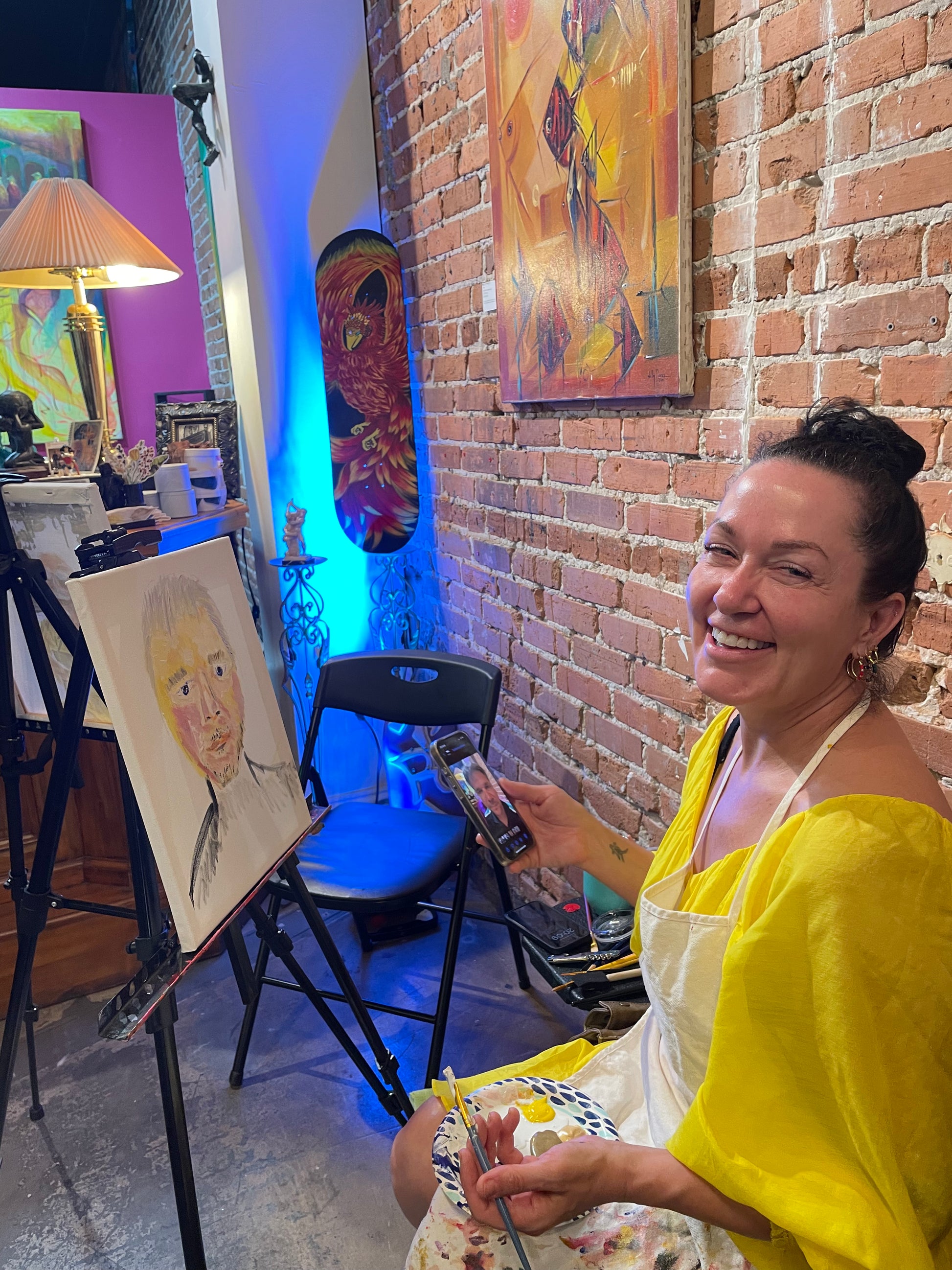 Guest smiling while painting during a relaxed sip and paint class at Marcolina’s Fine Arts Gallery.