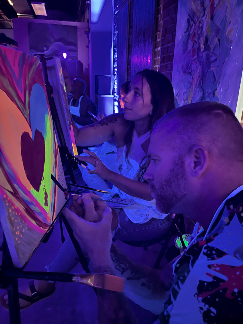 Guests painting under UV blacklights Marcolina's Neon Nights Tampa
