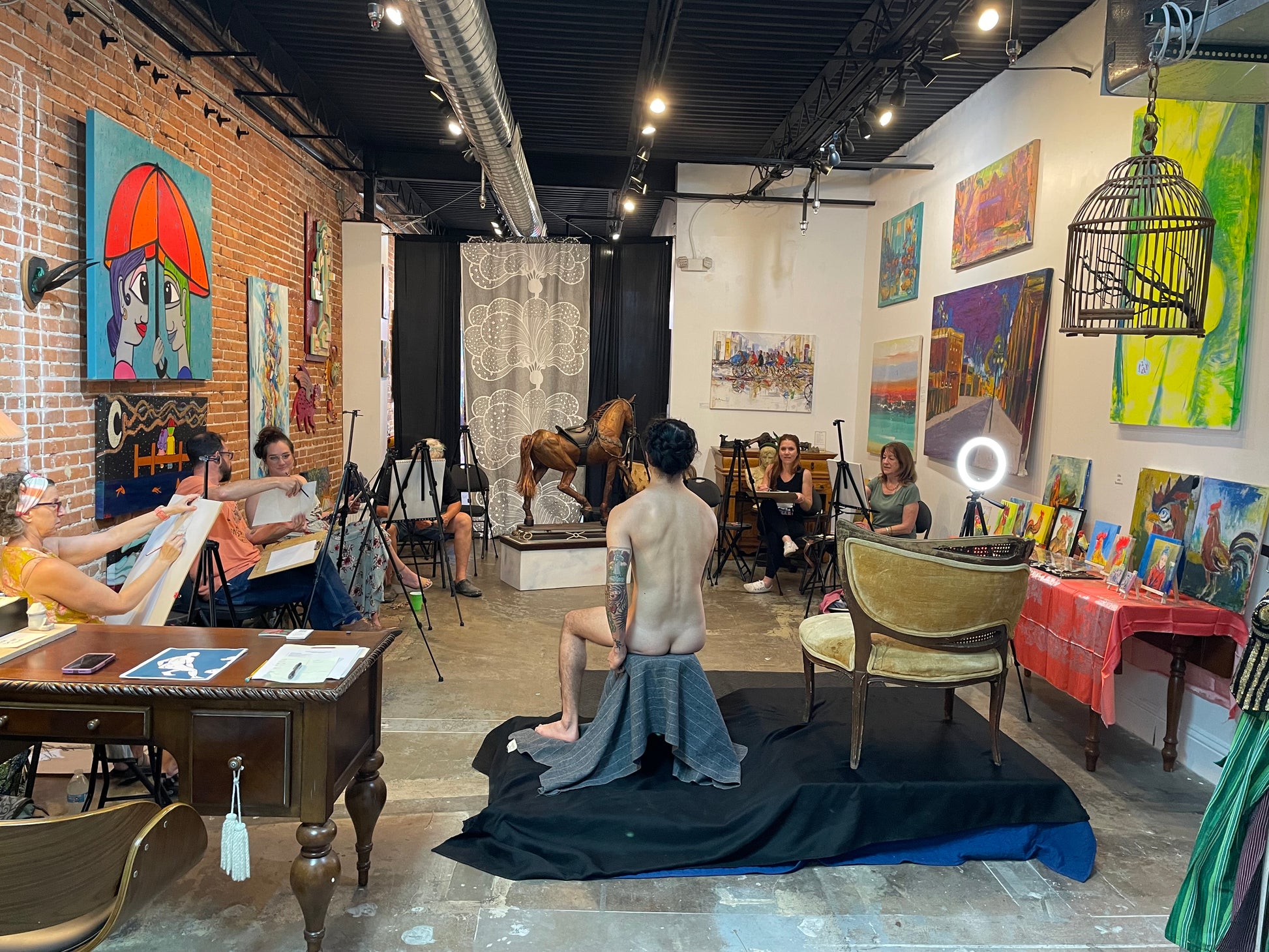 Figure drawing session with a male model where artists and guests are drawing the model at Marcolina's art gallery.